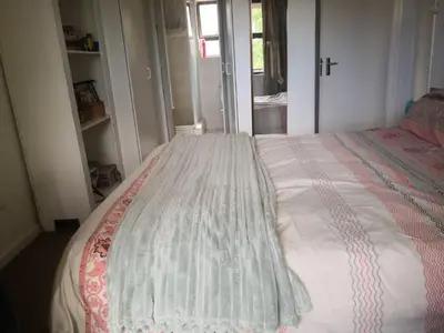 a bedroom with a bed with a comforter on it at Duplex in Tableview in Cape Town