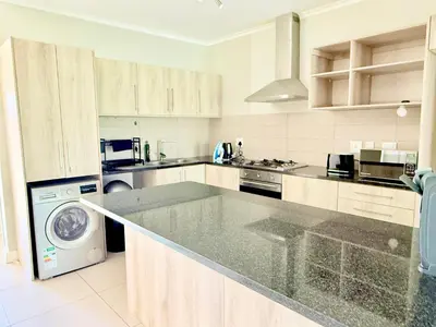 a large white kitchen with a washer and dryer at Luxe Manhattan Quarters in Cape Town