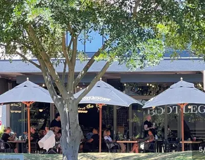 a group of people sitting at tables under umbrellas at Luxe Manhattan Quarters in Cape Town