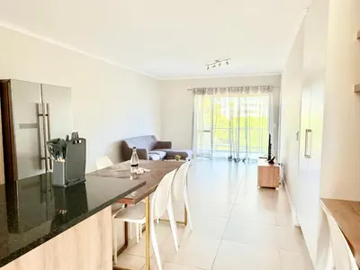 a kitchen and living room with a table and chairs at Luxe Manhattan Quarters in Cape Town