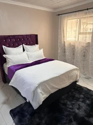 a bedroom with a large bed and a window at New Dawn Guest House in Goodwood