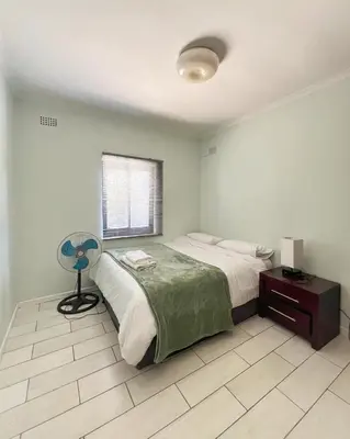 a bedroom with a bed with a fan and a window at Spacious house for 11 Guests near Canal Walk Mall in Cape Town