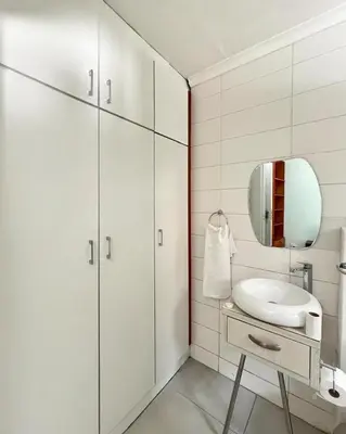 a white bathroom with a sink and a mirror at Spacious house for 11 Guests near Canal Walk Mall in Cape Town