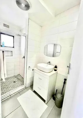 a white bathroom with a sink and a shower at Spacious house for 11 Guests near Canal Walk Mall in Cape Town