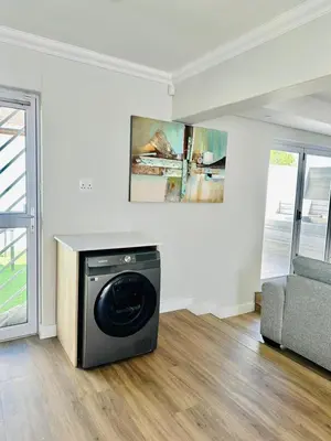 a washing machine in a living room with a couch at Spacious Family Friendly Richwood in Cape Town