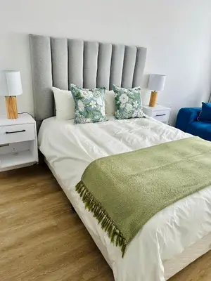 a bedroom with a large white bed with a green blanket at Spacious Family Friendly Richwood in Cape Town