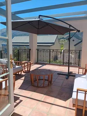 a patio with a table and an umbrella at L'Ermitage Villa Francois in Franschhoek