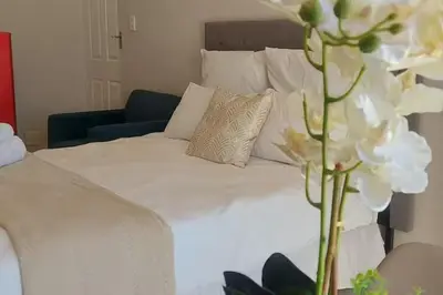 a bed with white sheets and a vase of flowers at Nemesia Suites in Cape Town