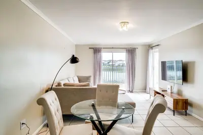 a living room with a couch and a glass table at Belina - Century On Lake Moorings in Cape Town