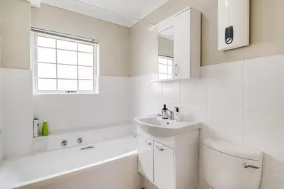 a white bathroom with a toilet and a sink at Belina - Century On Lake Moorings in Cape Town