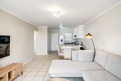 a living room with a white couch and a kitchen at Belina - Century On Lake Moorings in Cape Town