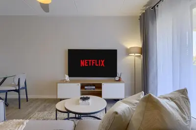 a living room with a tv and a couch at Nua Chic Stylish 1Bedroom - 2mins to Beach in Cape Town