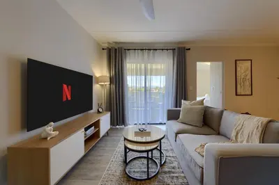 a living room with a couch and a tv at Nua Chic Stylish 1Bedroom - 2mins to Beach in Cape Town