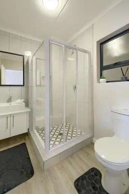 a bathroom with a shower and a toilet and a sink at Nua Chic Stylish 1Bedroom - 2mins to Beach in Cape Town