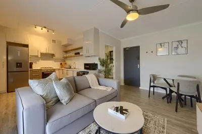 a living room with a couch and a table at Nua Chic Stylish 1Bedroom - 2mins to Beach in Cape Town