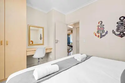a bedroom with a bed with a desk and a chair at Gordons Village View in Cape Town