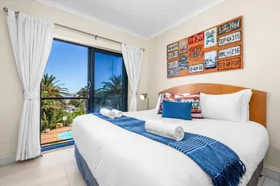 a bedroom with a large bed and a large window at Gordons Village View in Cape Town