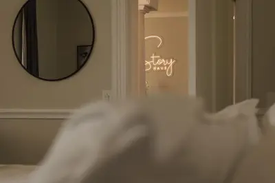 a mirror on a wall next to a bed with white pillows at Story Haus in Stellenbosch