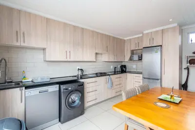 a kitchen with a washer and a wooden table at Entire large 1 bedroom very private with parking in Cape Town