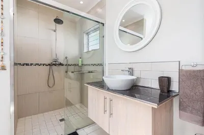 a bathroom with a sink and a shower with a mirror at Entire large 1 bedroom very private with parking in Cape Town