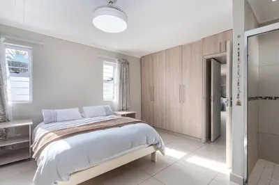 a white bedroom with a bed and a bathroom at Entire large 1 bedroom very private with parking in Cape Town