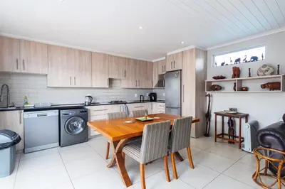 a kitchen with a wooden table with chairs and a stove at Entire large 1 bedroom very private with parking in Cape Town