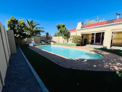a swimming pool in a yard next to a house at 4 Bedroom Bliss in Cape Town