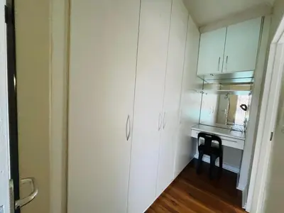 a small kitchen with white cabinets and a black stool at 4 Bedroom Bliss in Cape Town