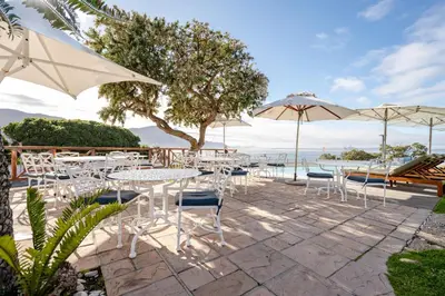 a patio with tables and chairs and umbrellas at Harbour House Hotel in Hermanus
