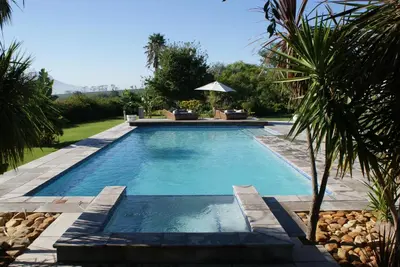 a swimming pool in a backyard with a palm tree at Wedgeview Country House & Spa in Stellenbosch