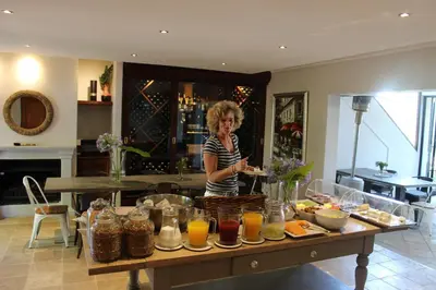 a woman standing in a kitchen with a table of food at Wedgeview Country House & Spa in Stellenbosch