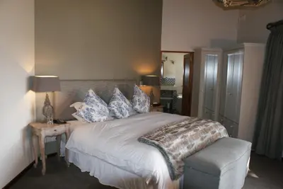 a bedroom with a large bed with blue and white pillows at Wedgeview Country House & Spa in Stellenbosch