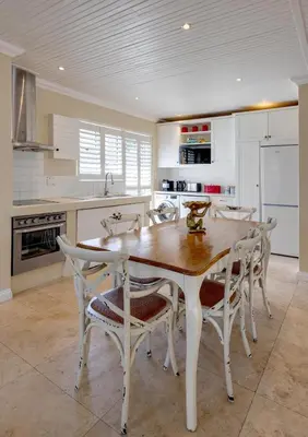 a white kitchen with a wooden table and chairs at Silencio in Hermanus