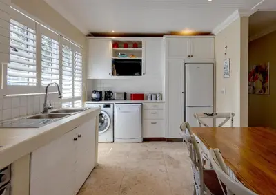 a kitchen with white appliances and a wooden table at Silencio in Hermanus