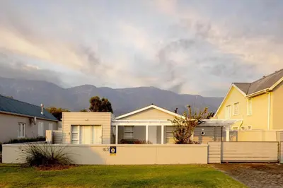 a house with a white fence and mountains in the background at Silencio in Hermanus