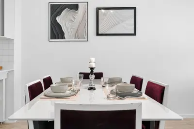 a white dining room table with chairs and a white wall at Modern Luxury 2BR Island Club Century City in Cape Town