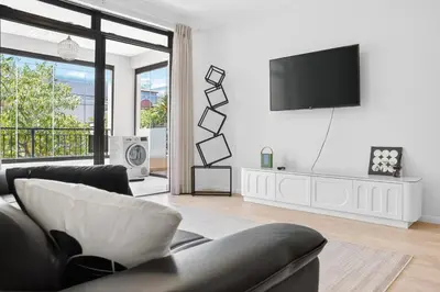 a living room with a couch and a tv on a wall at Modern Luxury 2BR Island Club Century City in Cape Town