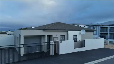 a white house with a black fence at Rachel`s Apartments - Stepney Crescent in Cape Town