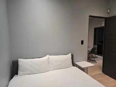a bedroom with a white bed and a table at Rachel`s Apartments - Stepney Crescent in Cape Town