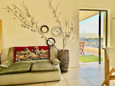 a living room with a couch and a clock on the wall at Cape Town Apartment with Table Mountain View in Cape Town
