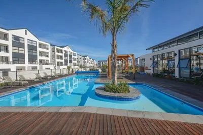 a swimming pool with a palm tree and some buildings at Cape Town Apartment with Table Mountain View in Cape Town
