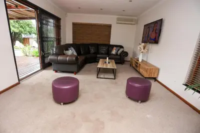 a living room with a leather couch and purple stools at African Oasis Kenya in Somerset West