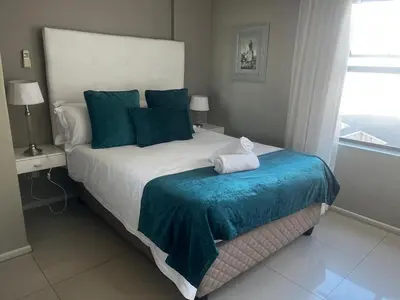 a bedroom with a large bed with a blue blanket at Aquarius Luxury Suites 406 in Cape Town