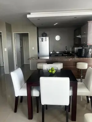 a kitchen with a dining room table and white chairs at Aquarius Luxury Suites 406 in Cape Town