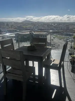 a wooden table and chairs on a balcony with a view at Aquarius Luxury Suites 406 in Cape Town