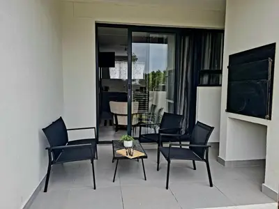 a living room with black chairs and a table at Cosy Apartment at Sitari Country Estate - Somerset West in Croydon