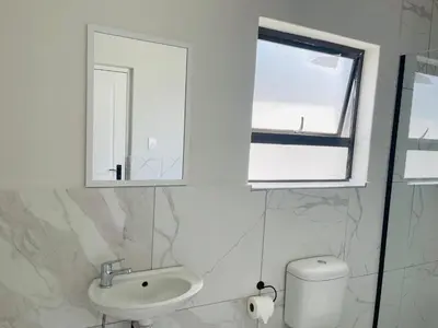 a bathroom with a sink and a window and a toilet at Maita Corner in Monte Vista