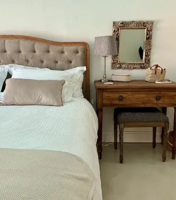 a bedroom with a bed and a table with a mirror at Elevené - one bedroom cottage with private pool in Franschhoek