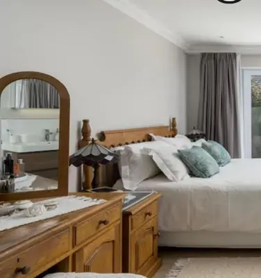 a bedroom with a bed and a mirror and a sink at Sues Suite in Somerset West