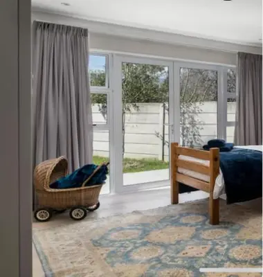 a bedroom with a bed and a chair and windows at Sues Suite in Somerset West